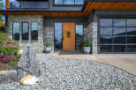 This stunning property boasts a modern facade with a beautiful stone exterior and a welcoming wooden door.