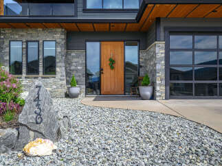 This stunning property boasts a modern facade with a beautiful stone exterior and a welcoming wooden door.