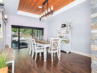 Step into this elegant dining room, featuring a stunning wood ceiling and a stylish chandelier.
