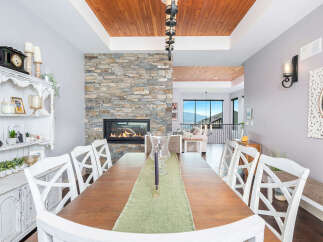 This stunning dining room boasts a cozy fireplace with a stone facade, perfect for creating a warm and inviting atmosphere.