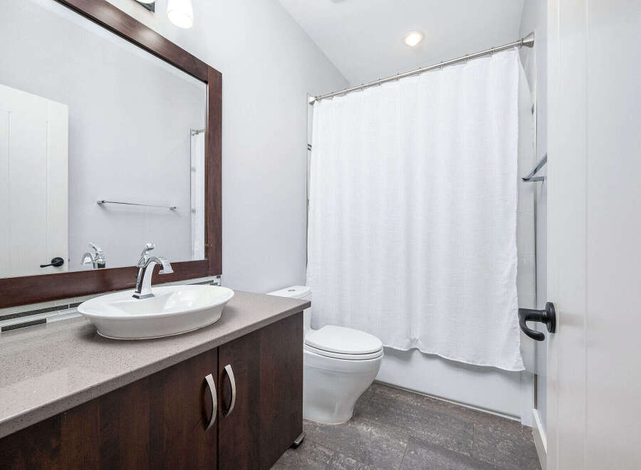 This modern bathroom features a sleek vanity with a stylish vessel sink and a large mirror.
