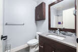 This modern bathroom features a sleek vanity with a stone countertop and a stylish dark wood cabinet.