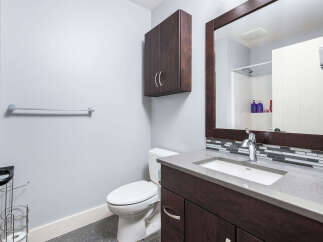 This modern bathroom features a sleek vanity with a stone countertop and a stylish dark wood cabinet.