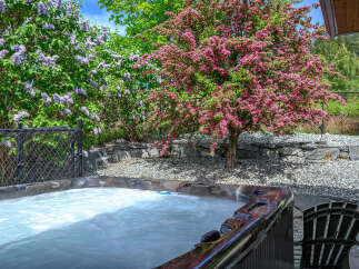 Relax and unwind in your own private oasis! This stunning property boasts a luxurious hot tub surrounded by lush landscaping and vibrant blooms.