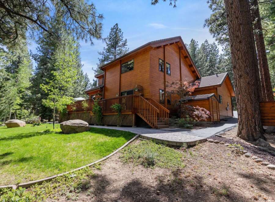 This stunning wooden cabin offers a serene retreat surrounded by lush greenery and towering trees.