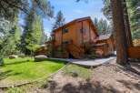 This stunning wooden cabin offers a serene retreat surrounded by lush greenery and towering trees.