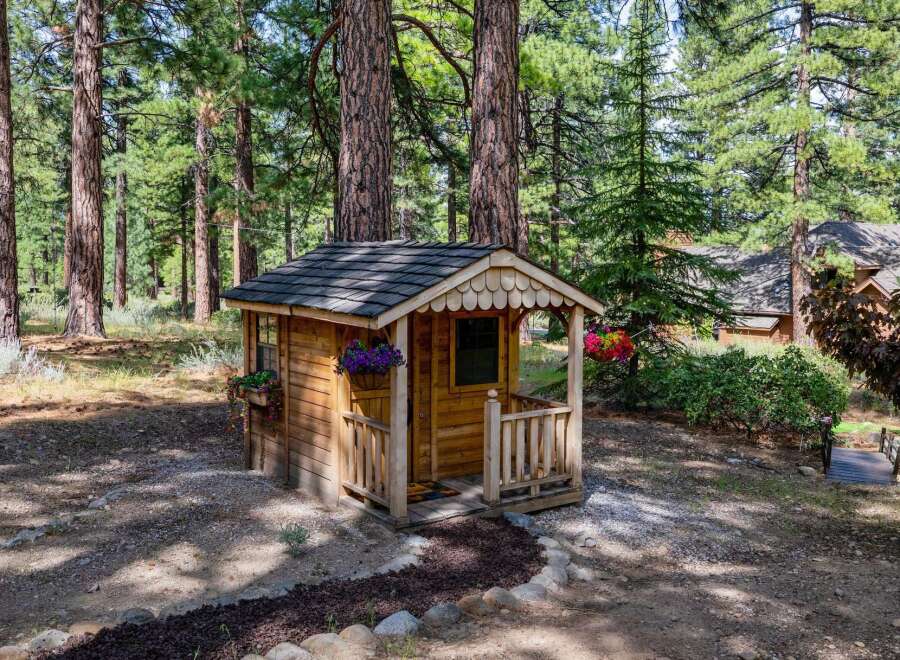 Nestled in a serene wooded setting, this charming wooden playhouse offers a delightful escape for children.