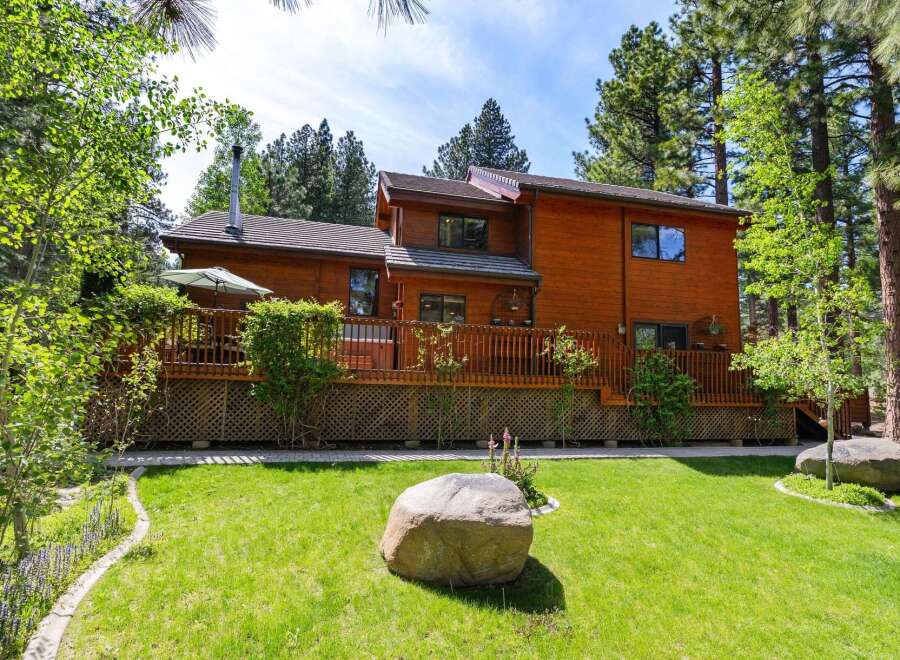 This stunning wooden cabin offers a serene retreat surrounded by lush greenery and towering trees.