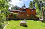 This stunning wooden cabin offers a serene retreat surrounded by lush greenery and towering trees.