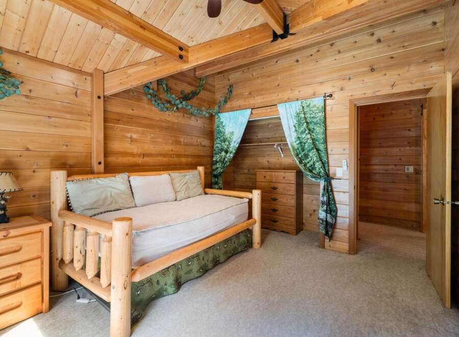 Step into a cozy retreat with this charming bedroom, featuring rustic wood paneling and a comfortable bed.