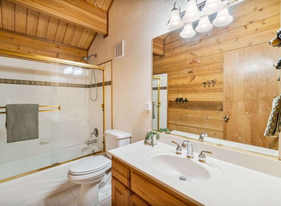 Step into this charming bathroom featuring a rustic wood accent wall and a bright, clean vanity.