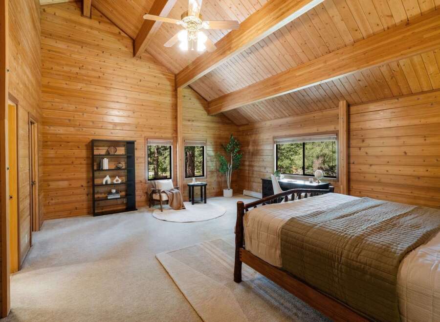 Step into this stunning bedroom featuring a warm, inviting ambiance with its wood-paneled walls and vaulted ceiling.