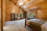 Step into this stunning bedroom featuring a warm, inviting ambiance with its wood-paneled walls and vaulted ceiling.