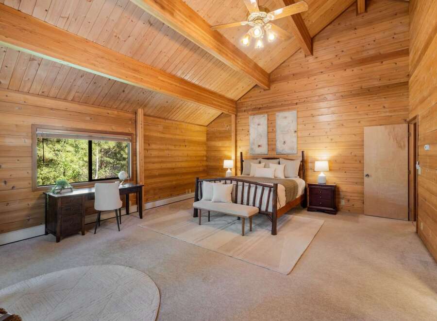 Step into a rustic retreat with this stunning bedroom featuring warm wood paneling and a vaulted ceiling.