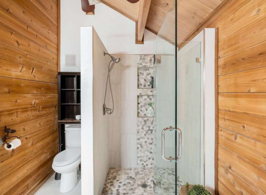 Step into a beautifully designed bathroom featuring natural wood accents and a modern glass shower.