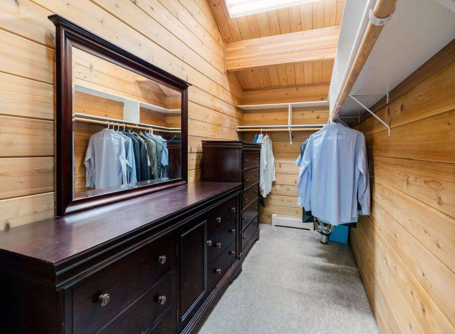 Step into luxury with this stunning walk-in closet, featuring rich wood paneling and ample storage.