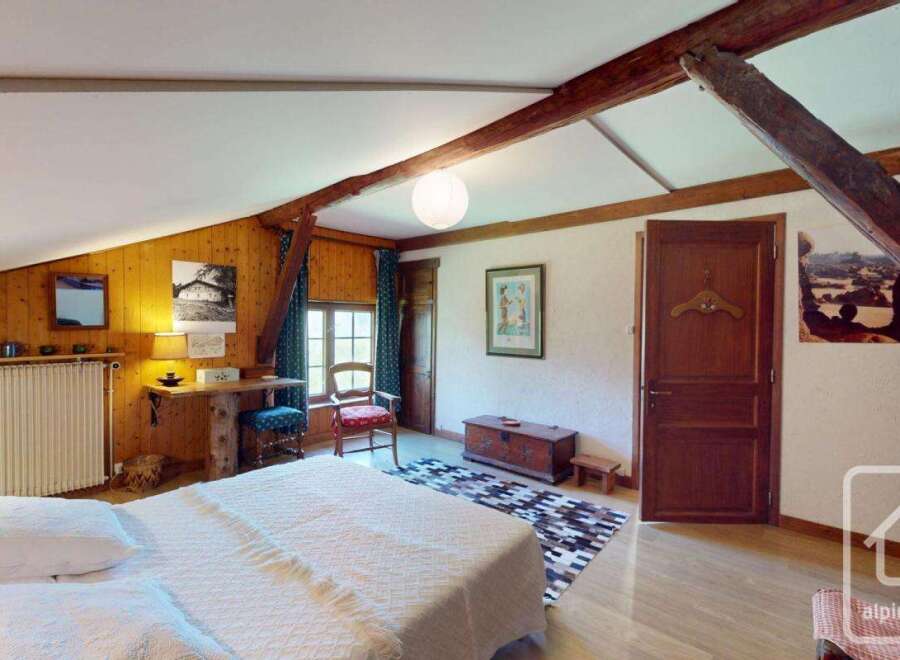 Discover the charm of this unique property, featuring a cozy bedroom with exposed wooden beams and a warm, inviting atmosphere.