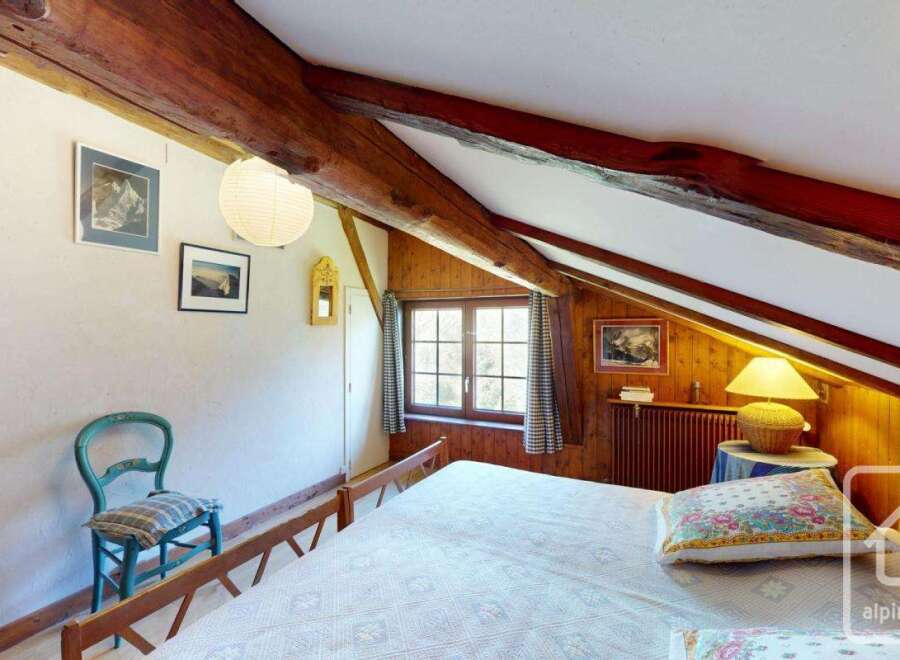 Discover the charm of this cozy bedroom, featuring exposed wooden beams and a warm, inviting atmosphere.