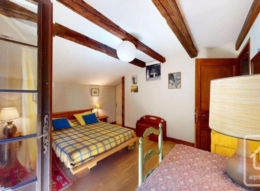 Discover the charm of this cozy bedroom, featuring exposed wooden beams and a warm, inviting atmosphere.