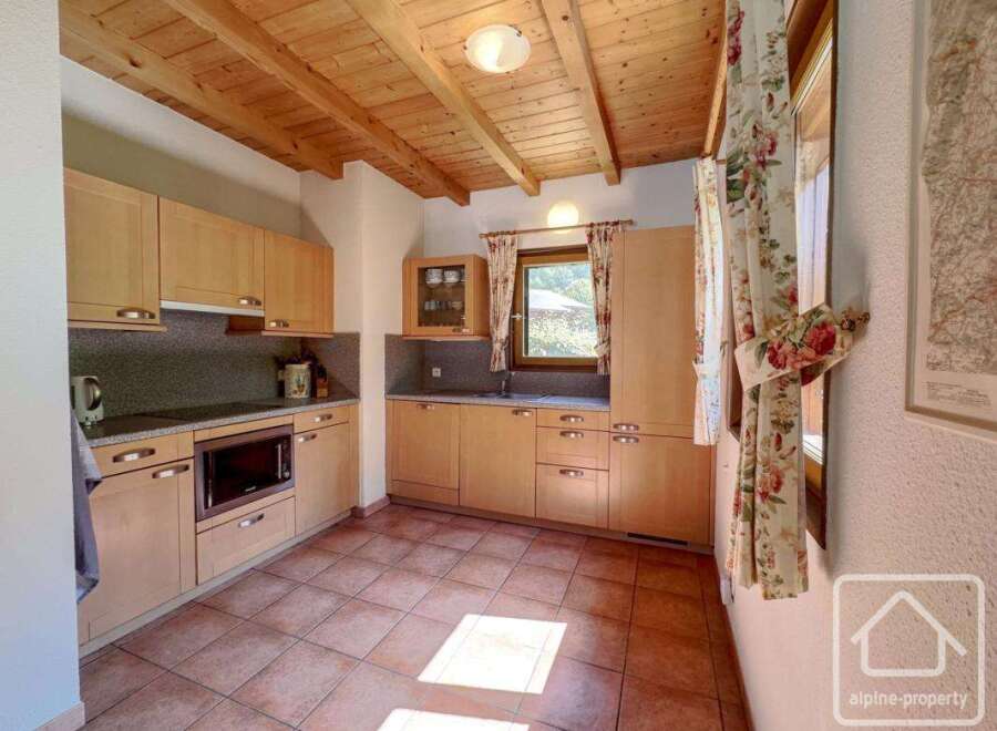 This charming kitchen boasts a warm and inviting atmosphere with its wooden ceiling and cabinetry.