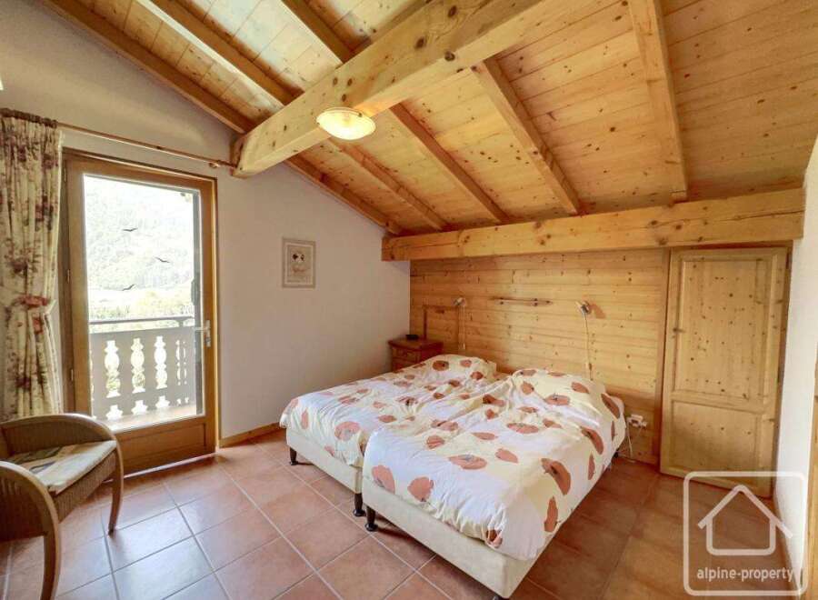 This charming bedroom boasts a cozy atmosphere with its wooden ceiling and walls, creating a warm and inviting space.