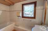 This charming bathroom features a cozy ambiance with its wooden ceiling and tiled walls.