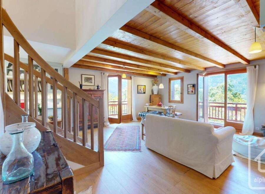 This stunning property boasts a warm and inviting interior with exposed wooden beams and a cozy living space.