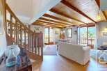 This stunning property boasts a warm and inviting interior with exposed wooden beams and a cozy living space.