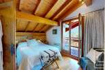 Discover the charm of this cozy bedroom, featuring a rustic wooden ceiling and a comfortable bed.
