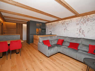 Experience modern living in this stunning property, featuring a stylish gray sectional sofa and vibrant red accent pillows.