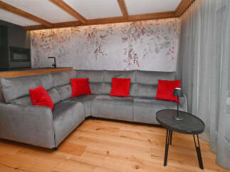 Discover modern living in this stylish property featuring a comfortable sectional sofa and vibrant red accent pillows.