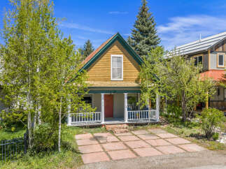 Charming cottage-style home with a welcoming front porch and a vibrant red door.