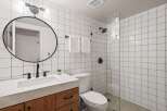 This modern bathroom features a sleek design with white square tiles and black accents.