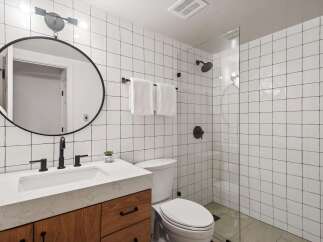 This modern bathroom features a sleek design with white square tiles and black accents.