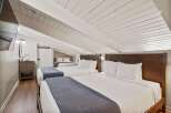 This charming bedroom features a unique sloped ceiling and exposed beams, creating a cozy and inviting atmosphere.