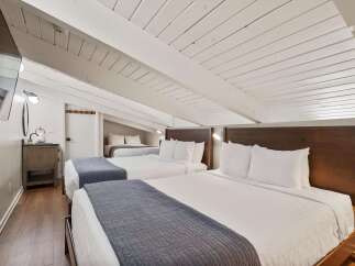 This charming bedroom features a unique sloped ceiling and exposed beams, creating a cozy and inviting atmosphere.