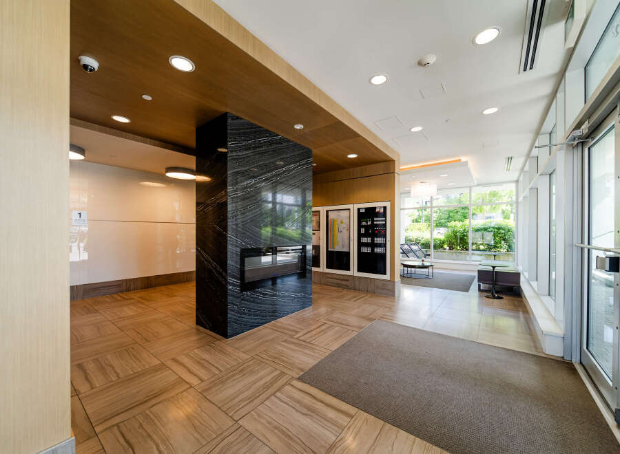 Step into the inviting lobby of this modern property, showcasing a sleek design with a striking black marble pillar and a built-in fireplace.
