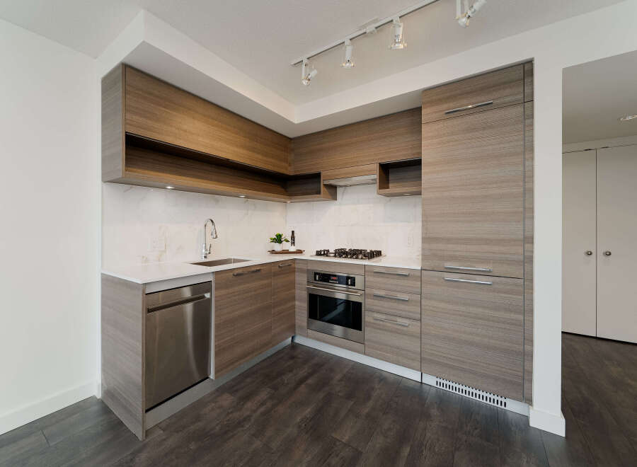This modern kitchen boasts sleek, wood-grain cabinetry and stainless steel appliances, creating a stylish and functional space.