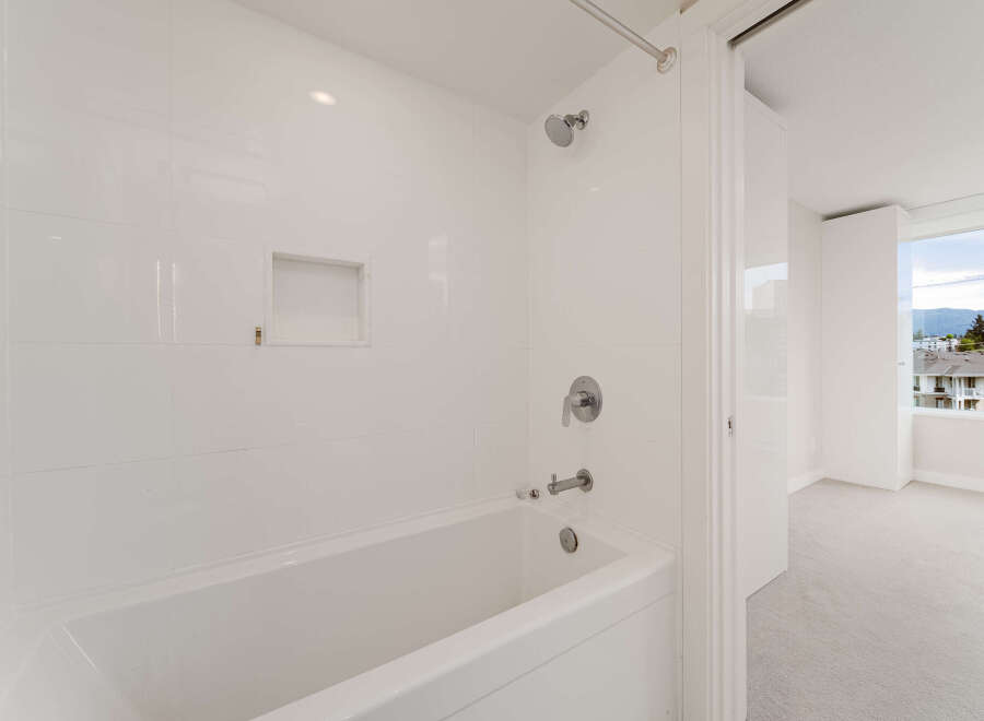Step into a pristine bathroom featuring sleek, white tile and modern fixtures.