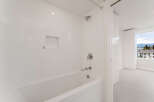 Step into a pristine bathroom featuring sleek, white tile and modern fixtures.