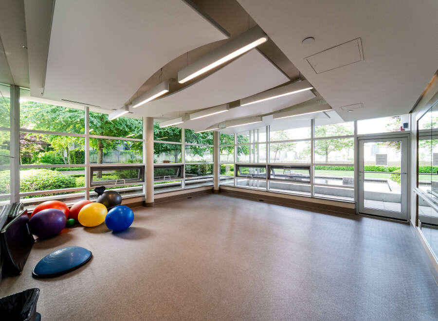 This bright and airy fitness room offers a serene space for workouts, featuring expansive windows that flood the room with natural light.