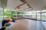 This bright and airy fitness room offers a serene space for workouts, featuring expansive windows that flood the room with natural light.