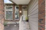 This charming home boasts a welcoming entrance with a brick facade and a covered porch.