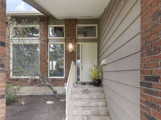 This charming home boasts a welcoming entrance with a brick facade and a covered porch.