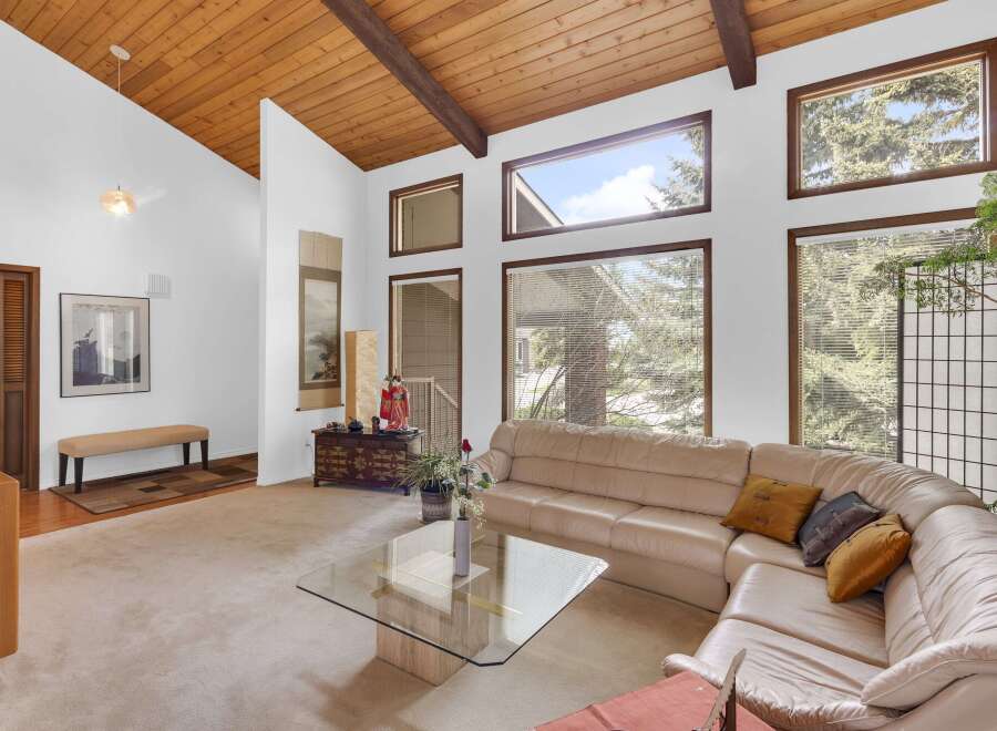 Step into luxury with this stunning property featuring a spacious living area with a unique wood-paneled ceiling and large windows that flood the space with natural light.