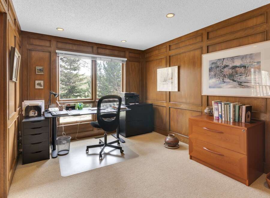 Step into this elegant home office, featuring rich wood paneling and a serene ambiance.