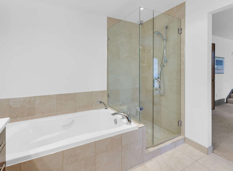This luxurious bathroom features a modern design with a sleek, white bathtub and a separate glass-enclosed shower.
