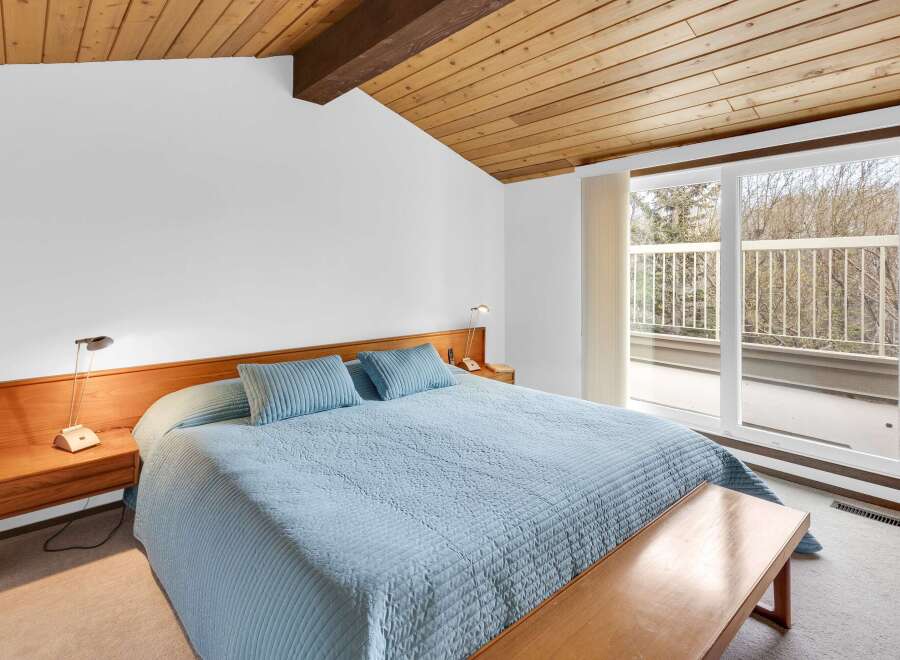 This bedroom offers a serene retreat with its light blue bedding and a wooden ceiling that adds warmth.