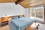 This bedroom offers a serene retreat with its light blue bedding and a wooden ceiling that adds warmth.