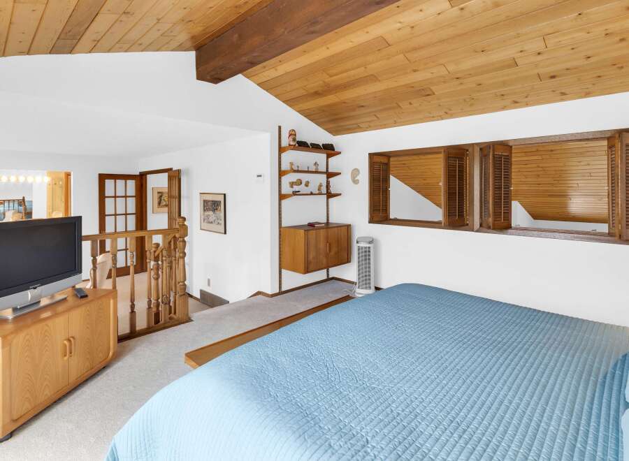 This stunning bedroom boasts a unique architectural design with a wooden sloped ceiling and a cozy ambiance.